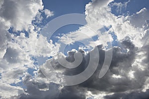 Beautiful day cloudscape view from below of fluffy dramatic white and grey clouds on a deep blue sky background