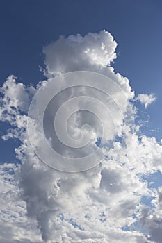 Beautiful day cloudscape view from below of fluffy dramatic white and grey clouds on a deep blue sky background