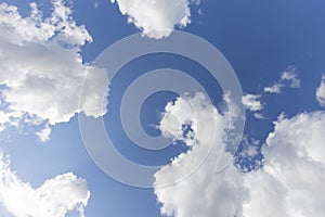 Beautiful day cloudscape view from below of fluffy dramatic white and grey clouds on a deep blue sky background