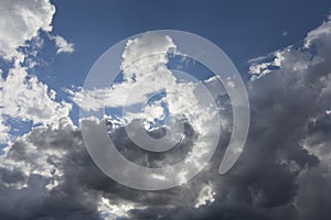 Beautiful day cloudscape view from below of fluffy dramatic white and grey clouds on a deep blue sky background