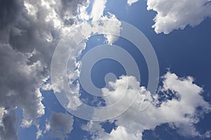 Beautiful day cloudscape view from below of fluffy dramatic white and grey clouds on a deep blue sky background