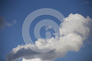 Beautiful day cloudscape view from below of fluffy dramatic white and grey clouds on a deep blue sky background