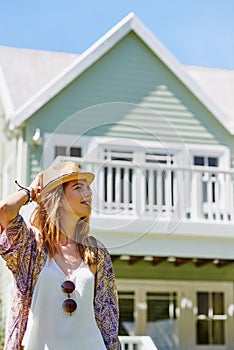 A beautiful day to be outdoors. Shot of an attractive young woman standing outside her home on a summers day.