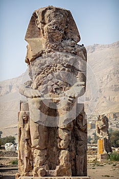 Beautiful daytime view of the Colossi of Memnon. Two large stone figures depicting a seated pharaoh.