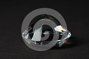 Beautiful dazzling diamond on dark background, closeup. Precious gemstone