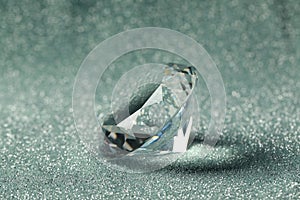 Beautiful dazzling diamond on shiny glitter background, closeup. Precious gemstone