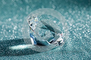 Beautiful dazzling diamond on shiny glitter background, closeup. Precious gemstone