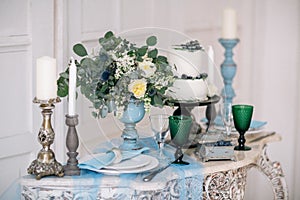 Beautiful decorate table with candles, vase with flowers and wedding cake on the table in studio