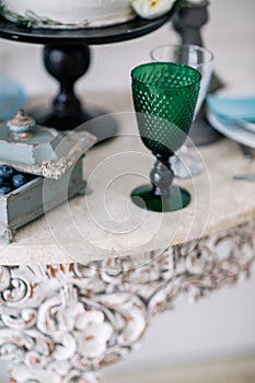 Beautiful decorate table with glass, candles, vase with flowers and wedding cake on the table in studio