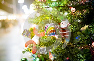 Beautiful decorated Christmas tree on blurred sparkling or bokeh background at night, decorate Xmas tree with Santa Claus doll,