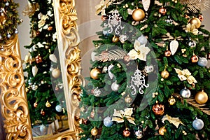 Beautiful decorated Christmas tree with red and goldish baubles and garland, in the new-year background with fireplace