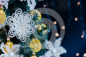 Beautiful decorated christmas tree with snow on the blurred bokeh of the garland. Holiday background