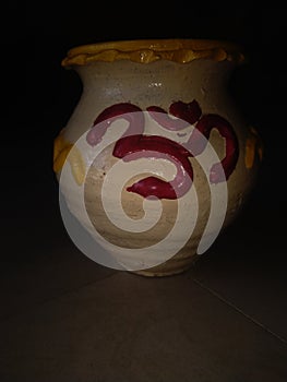 Beautiful decorated clay pot isolated on dark background.