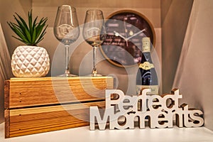 Beautiful decoration with glasses, whine, a clock and letters of perfect moments