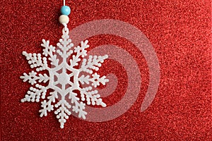 Beautiful decorative snowflake on sparkling red glitter background, closeup. Space for text