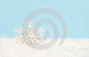 Beautiful decorative snowflake on white snow. blue background with space for text, greeting christmas card