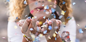 Beautiful defocused woman blow confetti from hands. celebration and event concept. happiness and coloured image. movement and