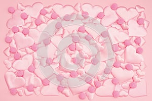 beautiful delicate background of voluminous pink satin hearts of different sizes and a fluffy balls arranged in the