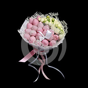 Beautiful delicate bouquet consisting of strawberries in pink chocolate and white roses stands in a glass vase on a black backgrou