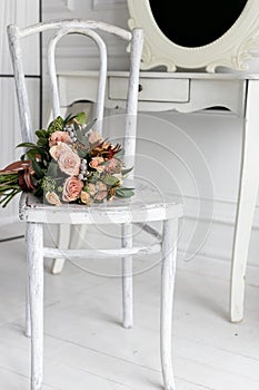 Beautiful delicate bouquet of cream roses lay on a white chair in a bright white room, bedroom
