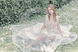 Beautiful delicate bride girl in a light beige wedding dress walks in the garden bright sunny warm day