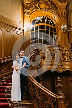 Beautiful delicate bride and handsome elegant groom embracing on old stairs with the background of gorgeous wooden