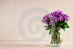 Beautiful delicate purple wildflowers in glass vase on the table with copy space. Minimalistic home decor. Floral