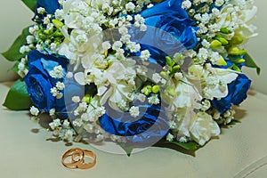 Beautiful delicate wedding bouquet of blue roses and wedding rings of the bride and groom