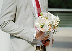 Beautiful delicate wedding bouquet of the bride in the hands of the groom