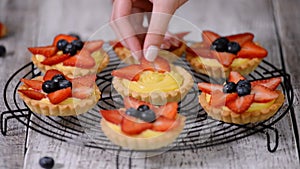 Beautiful delicious summer tartlets with fresh custard creamy filling topped with strawberry and blueberry