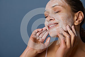 Beautiful delighted woman with perfectly healthy skin, holding hands on her face, performing smoothing massage, removing makeup