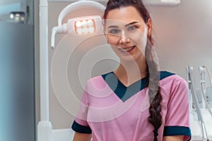 Beautiful dentis in pink uniform smiles on camera