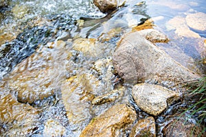 Beautiful detail of brilliant water flowing on rocks in bed of river