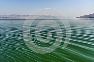 Beautiful detailed view of the green-blue waves on the Sea of Galilee Israel from a boat. in the distance the mainland with its mo