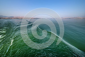 Beautiful detailed view of the green-blue waves on the Sea of Galilee Israel from a boat. in the distance the mainland with its mo