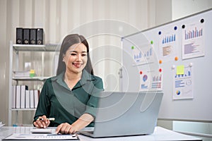 Beautiful determined business woman working using laptop and calculator calculating turnover in modern office