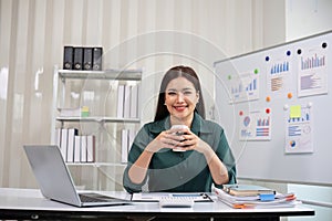 Beautiful determined business woman working using laptop and calculator calculating turnover in modern office