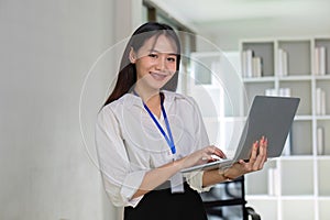 Beautiful determined business woman working using laptop recording data in modern office