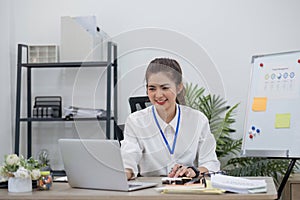 Beautiful determined business woman working using laptop recording data in modern office