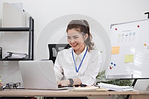 Beautiful determined business woman working using laptop recording data in modern office