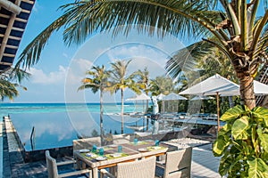 Beautiful dining set up white chairs and table near swimming pool at the tropical outdoor restaurant at island luxury resort