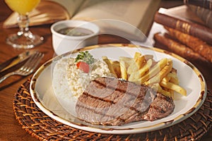 Beautiful dish of rice, beans and grilled meat. In the background old books