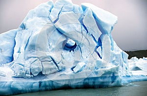 A beautiful  disintegrating and melting  iceberg with of blue ice and a hole inside