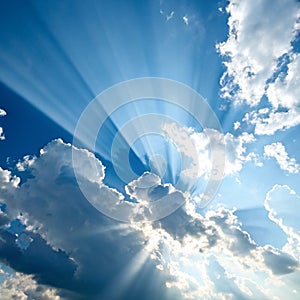 Rays of sunshine on a blue sky with a smattering of white clouds