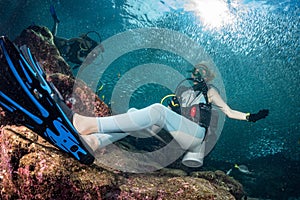 Beautiful diver in fish and corals reef background