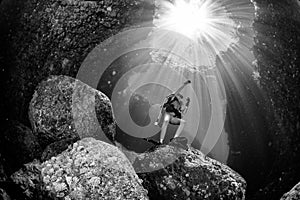 Beautiful diver underwater with sun rays