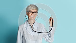Beautiful doctor with glasses listens through stethoscope