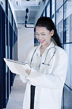 Beautiful doctor using digital tablet in corridor