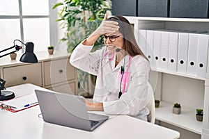 Beautiful doctor woman working on online appointment stressed and frustrated with hand on head, surprised and angry face