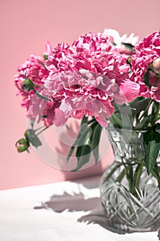 Beautiful double pink peony in glass transparent vase outdoor on pink background in a summer.
